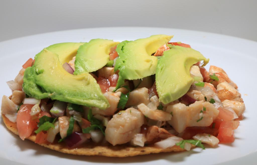 Ceviche Tostada · Shrimp and fish served with onion, cilantro, tomatoes, and avocado.