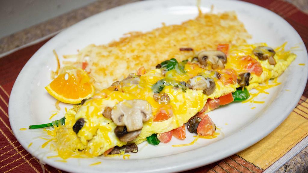 Veggie Omelette · Filled with Monterey jack and cheddar cheese, tomatoes, mushrooms and spinach. Served with breakfast potatoes or hash browns and toast.