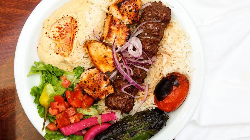Combo Kabab Plate · Beef and chicken  kababs, served with rice, red onions, roasted tomatoes, pepper, lettuce salad, pickles, hummus and pita bread.