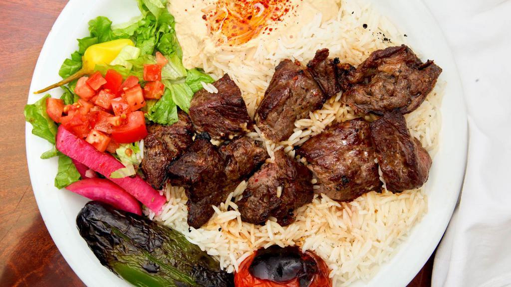 Beef Kabab Plate · Marinated beef served with rice, red onions, roasted tomato, pepper, pickles, hummus, lettuce salad, and pita bread.