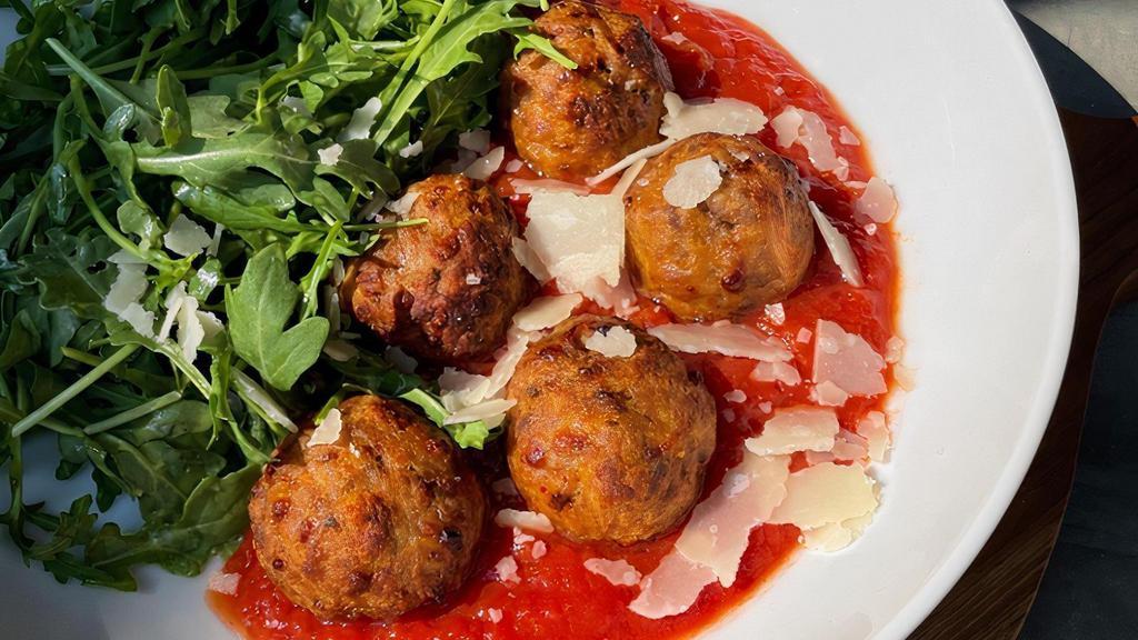 Meatballs In Harissa Tomato Sauce · A blend of grassfed beef and pork meatballs bathed in DiNapoli tomato sauce and topped with parmesan cheese. Served with a zesty arugula caesar salad.