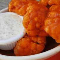 Cauliflower Buffalo Wings (V) · Grilled florets in a spicy pepper sauce served with Vegan Ranch dressing.