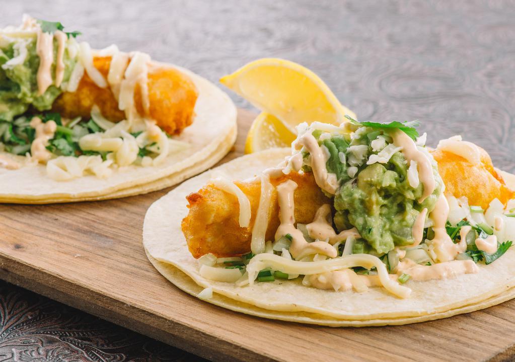 Fish Taco Especial · Lightly fried mahi filets with fresh guacamole, cilantro, red onion, queso blanco and chipotle crema on grilled corn tortillas.