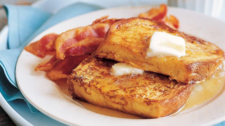 Classic French Toast · Four slices of thick, egg-washed cinnamon bread with maple syrup and powdered sugar.