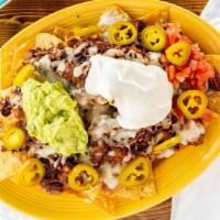 Nachos · Tortilla chips, beans, cheese, sour cream, guacamole, tomatoes, jalapeños & your choice of m...