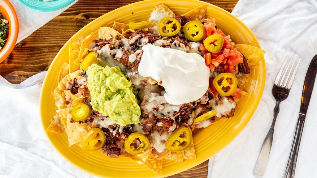 Nachos · Tortilla chips, beans, cheese, sour cream, guacamole, tomatoes, jalapeños & your choice of meat