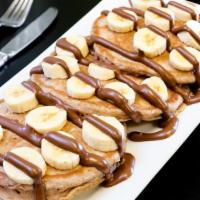 Banana & Nutella Pancakes · Three fluffy pancakes melted nutella and banana on top.