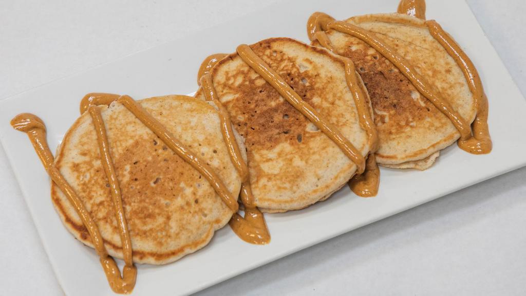 Peanut Butter Cream Pancakes · Three fluffy protein pancake with melted peanut butter on top.