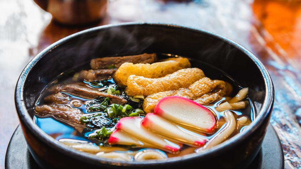 Beef Udon · Udon noodles, aburaage, fish cake, and beef topped with green onions and seaweed, served in a dashi broth
