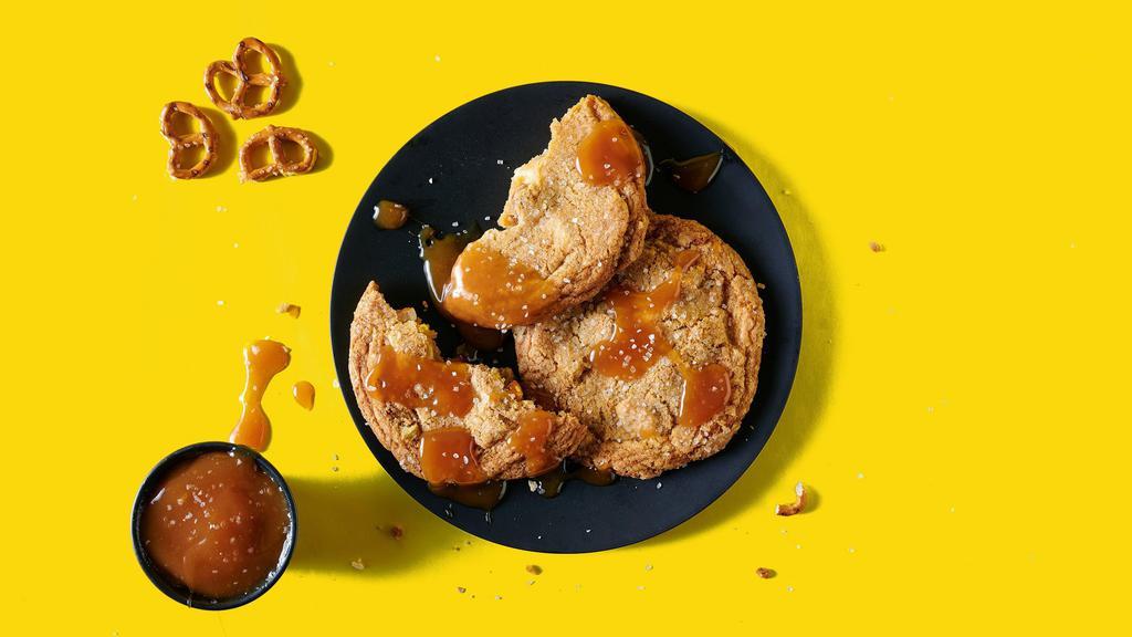 So Baked Hybrid Cookies · Two salted caramel cookies with chocolate and pretzel pieces, complete with oozy salted caramel dipping sauce to conquer all of your craves from salty to sweet