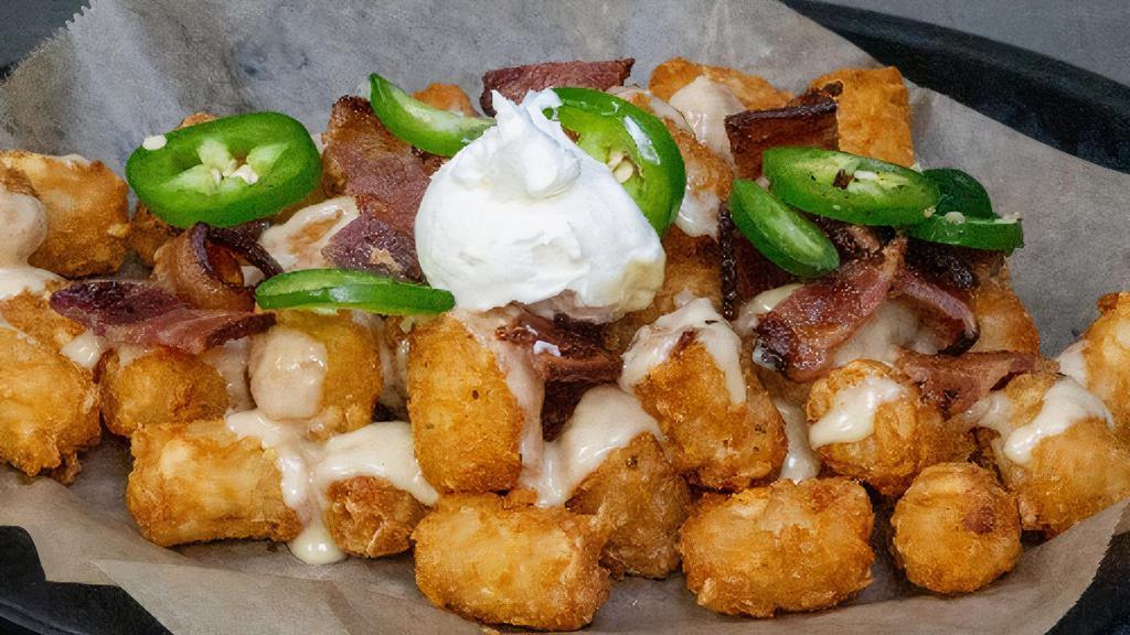 Rapture Tots · Tater Tots Topped with IPA Cheddar Sauce, Bacon, Jalapenos & Sour Cream