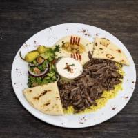 Beef Shawarma Plate · Served on a bed of yellow rice, side salad, hummus, pita bread, and tahini sauce.