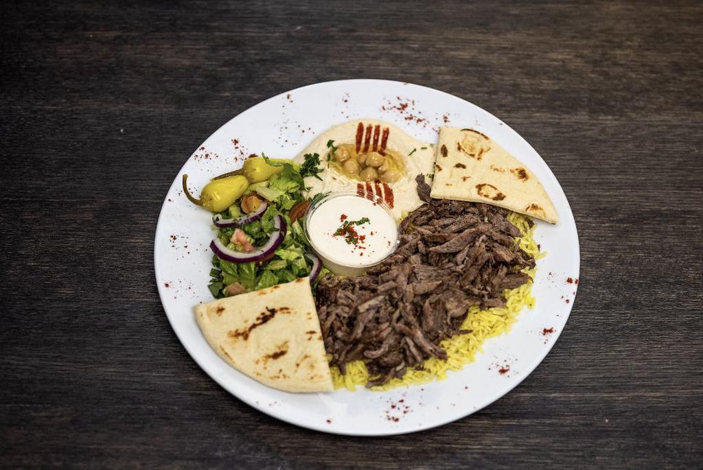 Beef Shawarma Plate · Served on a bed of yellow rice, side salad, hummus, pita bread, and tahini sauce.