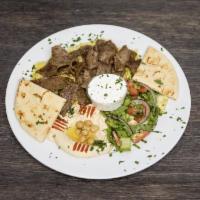Gyro Plate · Served on a bed of yellow rice, side salad, hummus, pita bread, and tzatziki sauce.