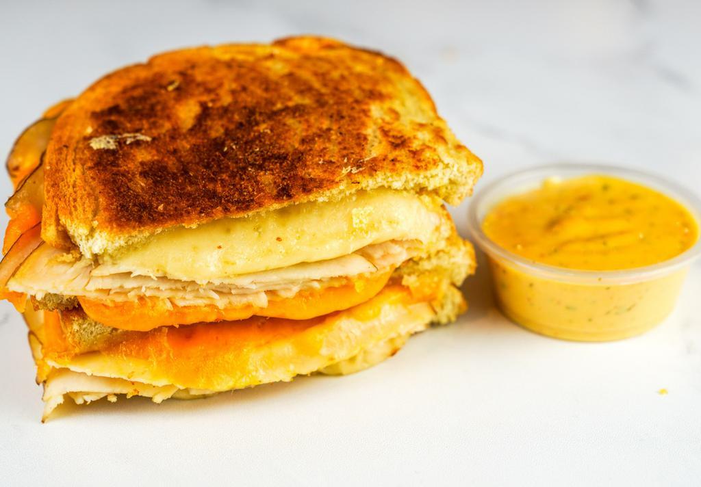 Roasted Turkey & Three Cheese Melt · Roasted turkey, Cheddar, Swiss, and Parmesan cheeses melted between buttery, toasted sourdough bread. Served with a side of Spicy Honey Mustard Aioli.