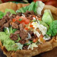 Shredded Beef Supreme Tostada · Served with beans, lettuce, salsa fresca, guacamole, sour cream, and cheese.