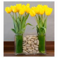 Modern Dutch Tulips · 20 yellow tulips in a rectangular glass vase with river rocks.