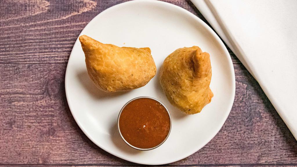 Vegetable Samosa · Vegan. Two samosas filled with spiced potato, cabbage, green onion, peas wrapped in a thin layer of flour dough and fried crisp. Served with tamarind sauce.