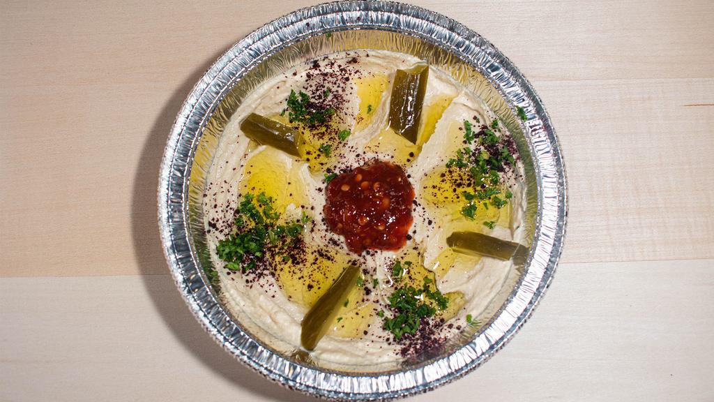 Hummus · Ground chickpeas with sesame sauce, blended with lemon juice, garlic and extra virgin olive oil. Served with fresh pita bread and assorted pickles.