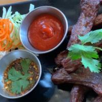 Thai Beef Jerky · Deep-fried marinated beef in authentic Thai-style served with sriracha and jaew dipping sauce.