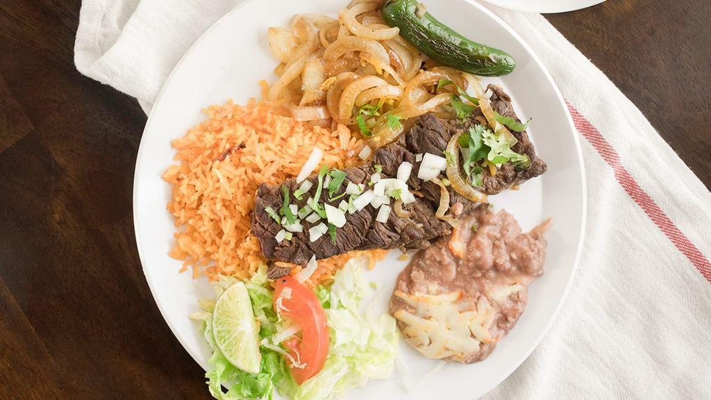 Carne Asada Plate · Grilled beef steaks served with rice, beans, and salad