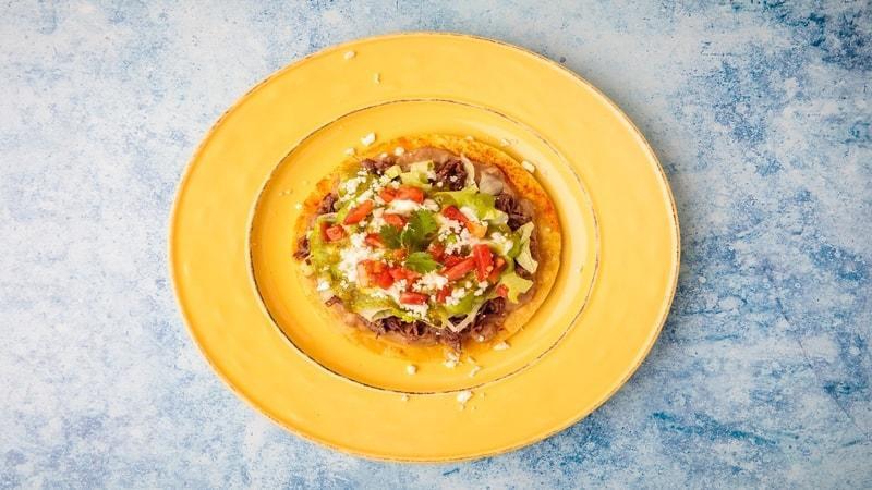 Tostada · Choice of Protein, Beans, Lettuce, Tomatoes, Sour Cream, Guacamole Sauce, Cheese & Salsa
