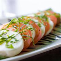 Caprese Salad · Slices fresh mozzarella cheese, tomatoes, julienne basil, and topped with a balsamic reducti...