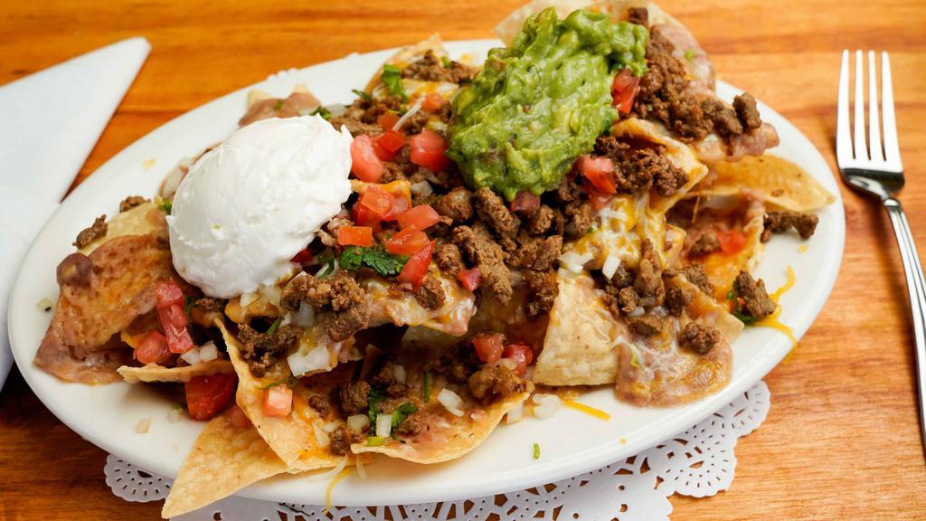 Nachos · Tortilla chips topped with beans, jack cheese, sour cream, guacamole, and pico de gallo,add  choice of meat.