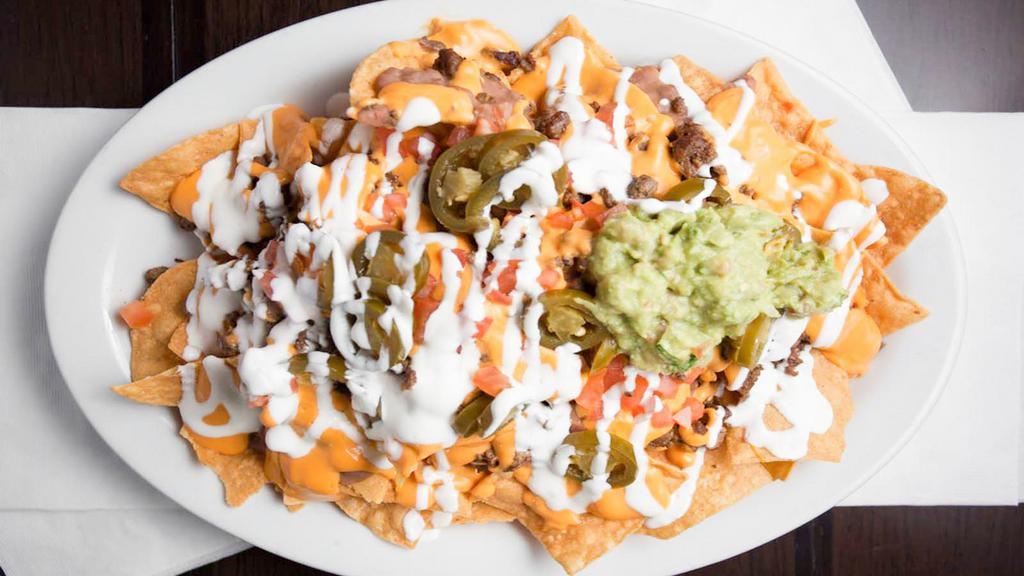 Super Nachos · Deep fried tortilla chips, topped with choice of meat, refried beans, choice of nacho or jack cheese, tomato, sour cream, guacamole and jalapeños.