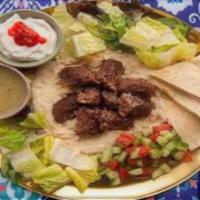 Ground Beef And Lamb Kabob Hummus Platter · Ground beef and lamb kabob served over hummus with salad, grilled tomatoes, pita, and your c...