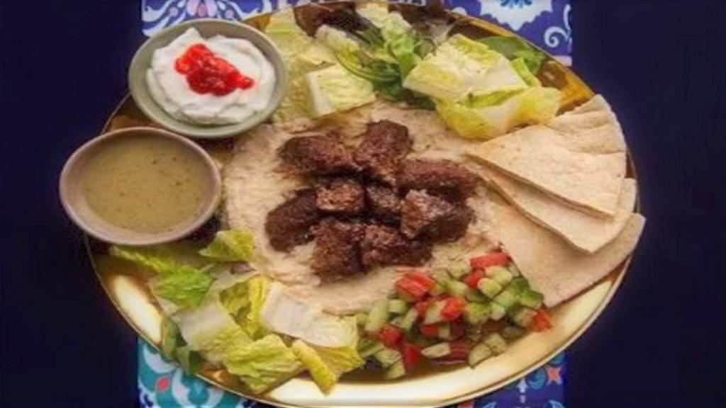 Ground Beef And Lamb Kabob Hummus Platter · Ground beef and lamb kabob served over hummus with salad, grilled tomatoes, pita, and your choice of sauce.