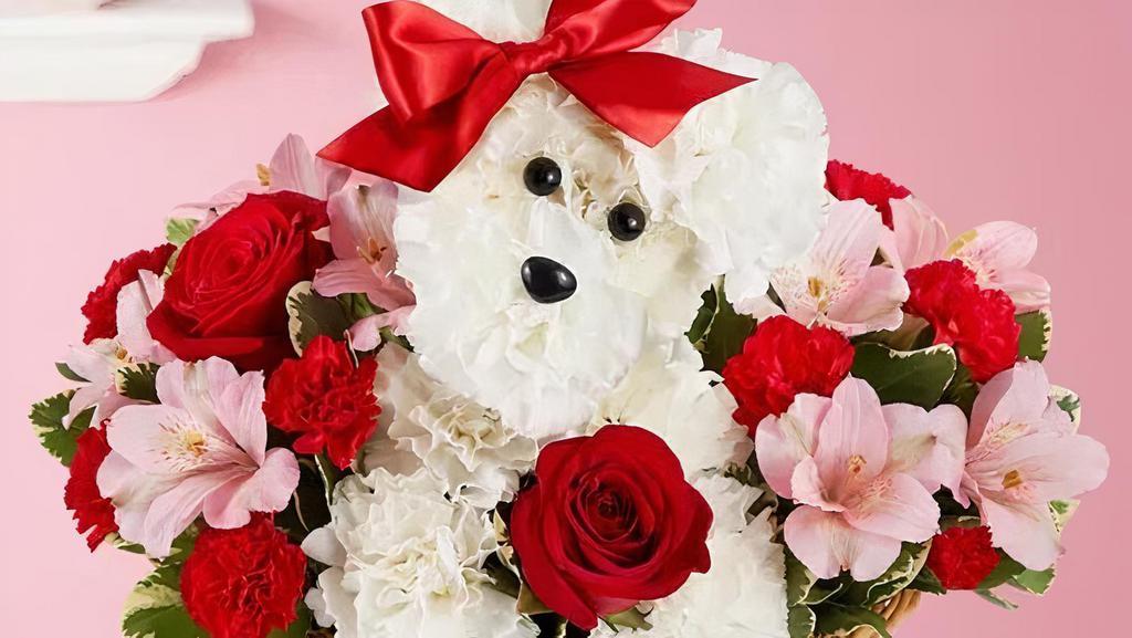 Love Pup · Celebrate your relationship with this cute gesture! Crafted from lasting white carnations, our canine cutie is sitting pretty in a dog bed basket, surrounded by a mix of red and pink blooms