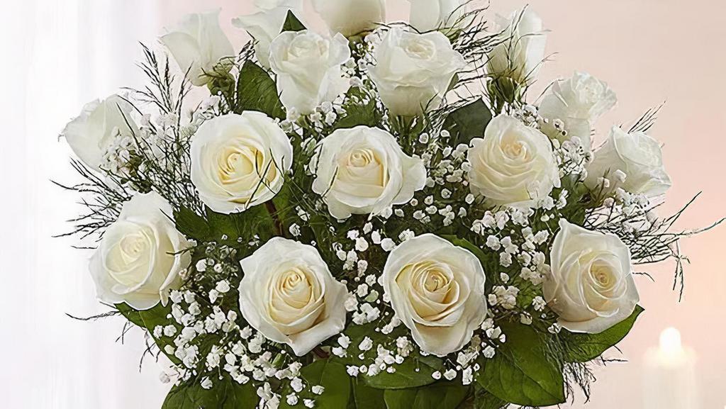 Rose Elegance™ Premium 12 Long Stem White Roses · You can never go wrong with white roses!. Arranged in a clear vase our roses are gathered with lush greenery.