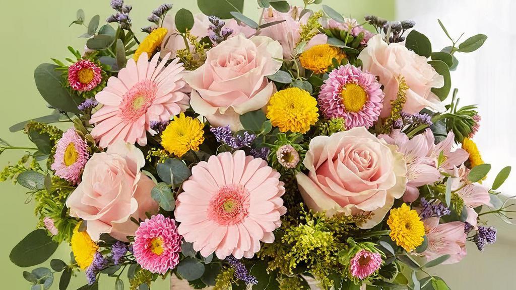 Spring Sentiment™ Bouquet · This bouquet represents everything Spring. Soft pink and yellow blooms are loosely gathered with lush greenery for style and texture. Designed in our rustic, grey-washed wooden cube.