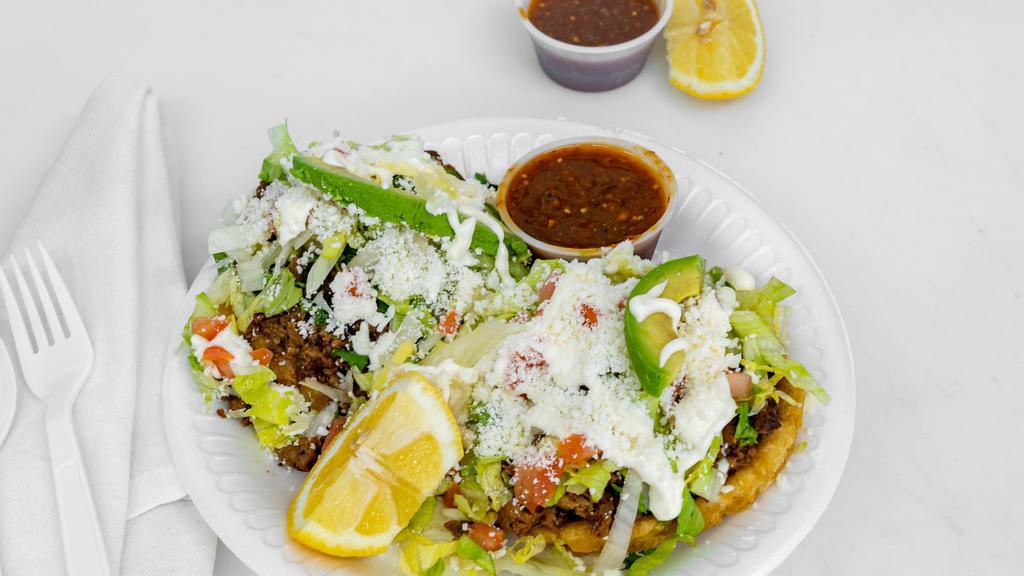 Sope · Meat of your choice, beans, cilantro, lettuce, tomato, avocado, queso cotija, and sour cream.  Image is an order of two sopes.