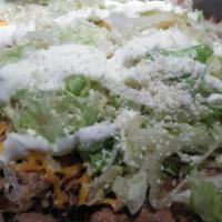 Carne Asada Tostada · Topped with beans, sour cream cheese, lettuce, and cotija cheese.