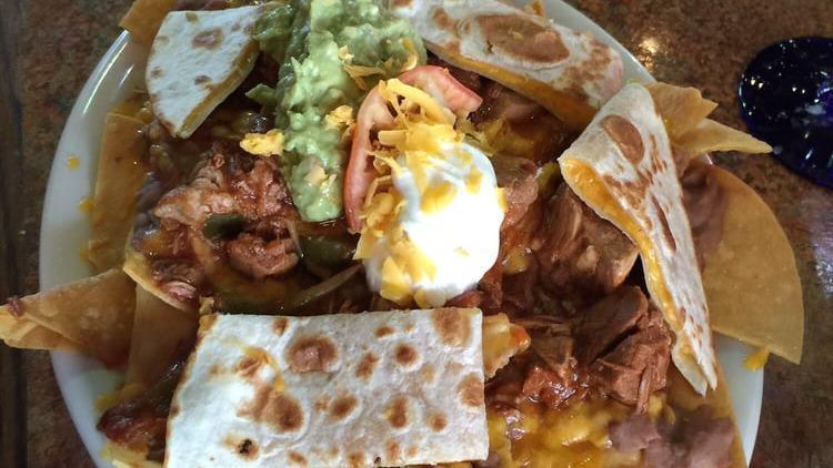 Nachos Supreme · Tortilla chips topped with refried beans, cheddar cheese, guacamole, sour cream, mini quesadillas, and your choice of beef, shredded chicken, or cubed pork.