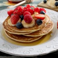 Strawberry, Blueberry, And Banana Pancakes · 2 fluffy, freshly made pancakes with strawberries, blueberries, and bananas.