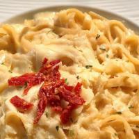 Fettuccine Alfredo · Fettuccine tossed with house-made Alfredo sauce, roasted garlic, sun-dried tomatoes, and Par...