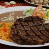 Steak Plate · One juicy Rib-Eye beef steak served with rice, beans, salad, and tortillas.