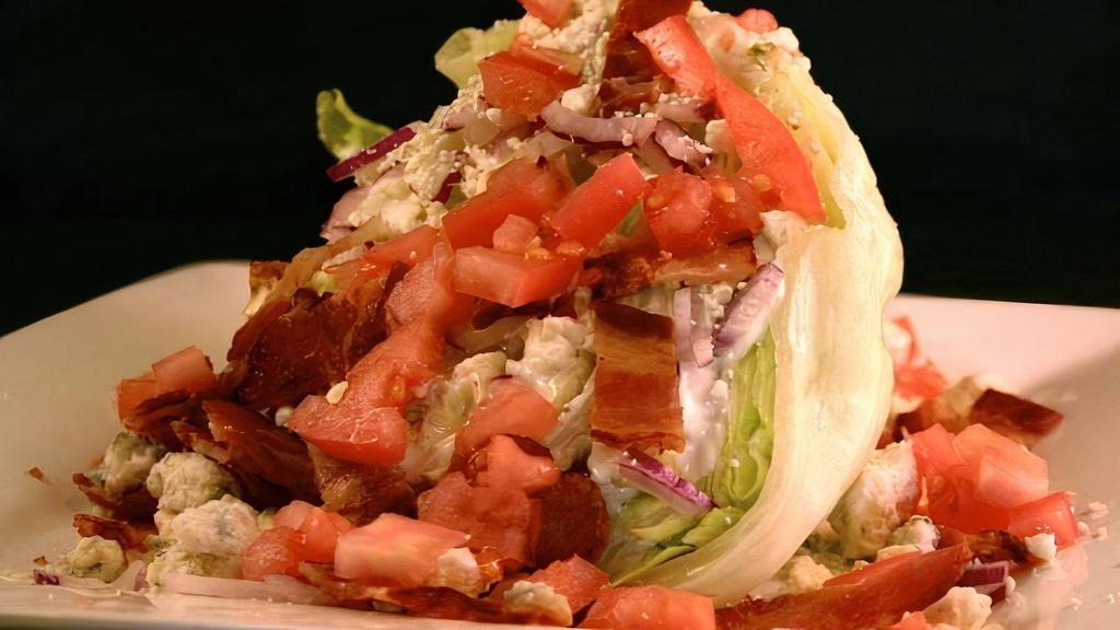 Iceberg Wedge Salad · Wedge of iceberg lettuce topped with creamy bleu cheese dressing, fresh diced tomatoes, red onions, bleu cheese crumbles and chopped bacon.