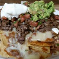 Nachos · Warm corn tortilla chips covered in refried beans and melted cheese.
