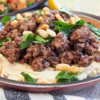 Hummus Kaworma · Hummus topped with seasoned, cooked mince meat and pine nuts.