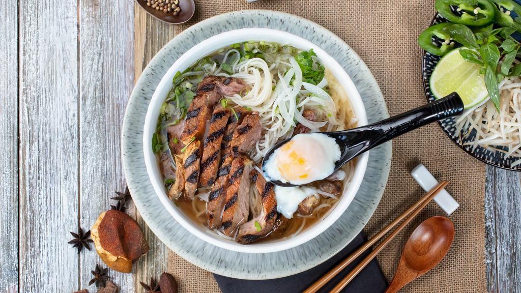 Phở Bò Bít Tết (Steak) · 8oz juicy seared rib-eye steak and a poached egg; served in our 12-hour bone broth. East meets West, the best of both world.
