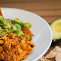 Vegan Chilaquiles · Corn chips sauteed with tofu scramble and house-made red salsa. Topped with avocado and hous...