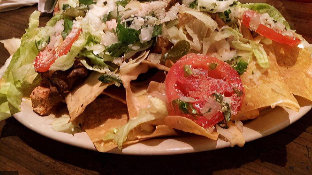 Nachos · Corn tortilla chips, spread with refried pinto beans, topped with melted cheese, pico de gallo, jalapenos, sour cream, and guacamole.