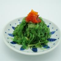 Seaweed Salad · Seaweed salad, accompanied by sliced cucumbers, shaved carrot and red cabbage.