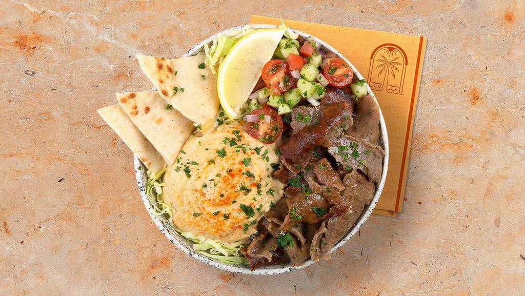 Beef And Lamb Gyro Hummus Bowl · Marinated beef and lamb over hummus, diced cucumber and tomato salad, shredded green cabbage and a drizzle of tahini sauce.