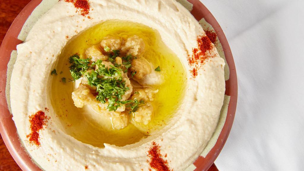 Hummus · Boiled and mashed chickpeas mixed with tahini, lemon and topped with olive oil, served with pita bread.