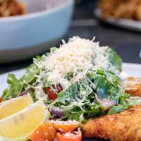 Chicken Milanese · Pan-fried thin crisp chicken breast topped off with arugula, onions, tomatoes, and parmesan ...